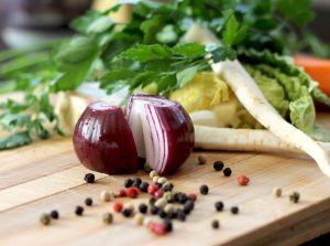 onion and whole peppercorns on a cutting board